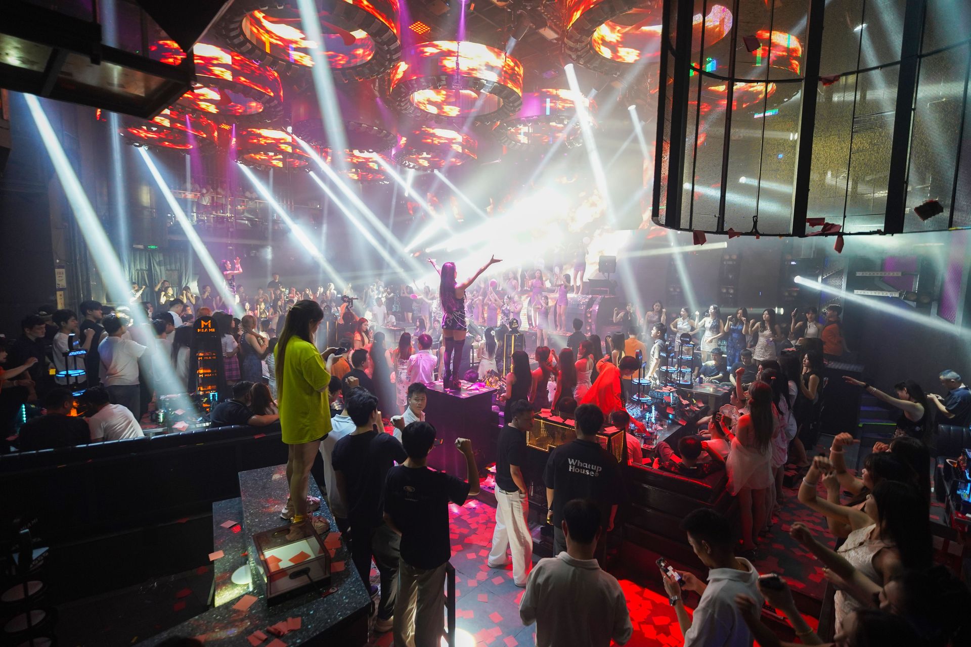 Crowded nightclub with vibrant lighting and people dancing, capturing nightlife energy.
